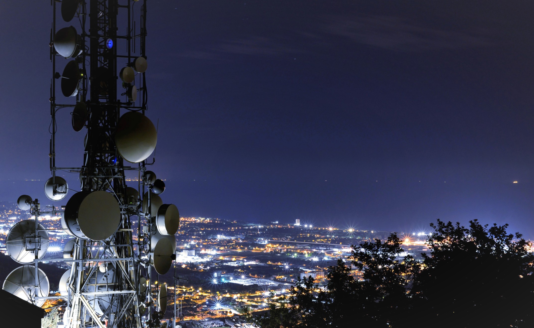 telecommunications tower antenna and satellite dish and city at night as background